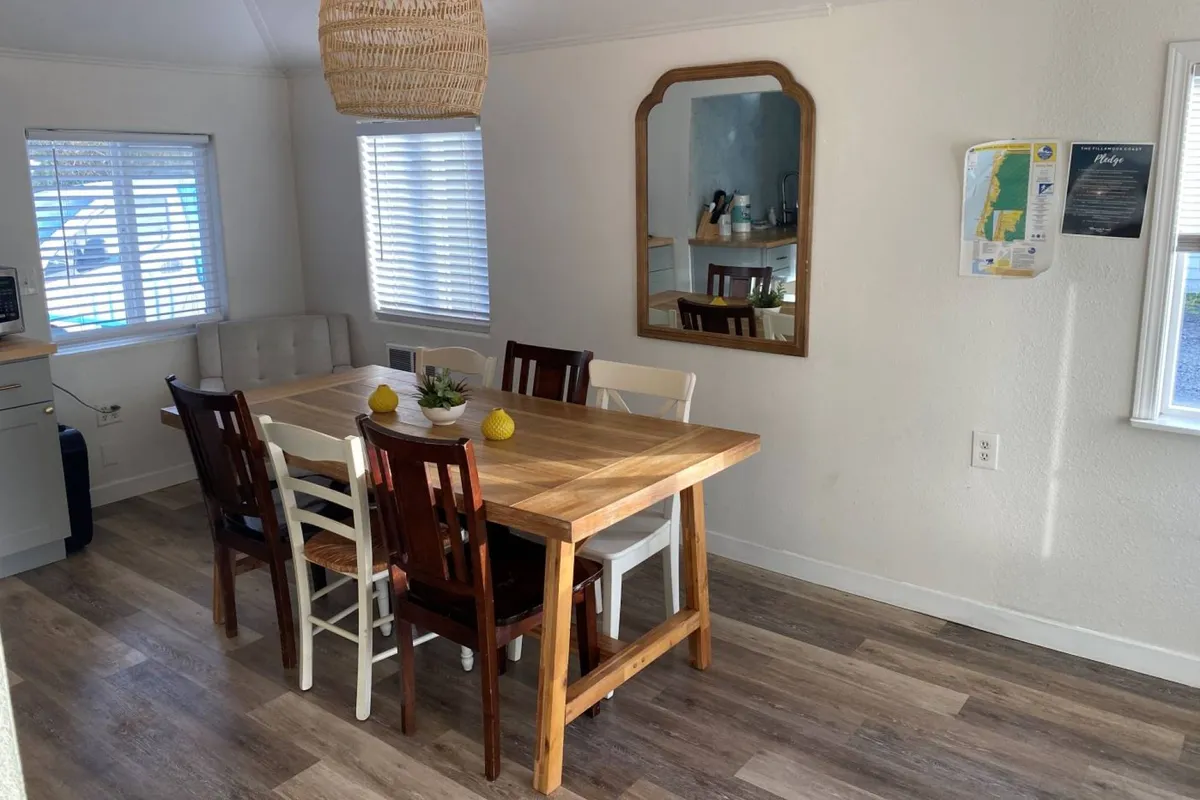 Warm, welcoming dining area featuring a dining table with seating, a mirrored wall that enhances the sense of space, and a hanging lamp for ambiance. The setup easily accommodates family meals, group gatherings, or work-from-home sessions, with décor that feels both fresh and inviting.